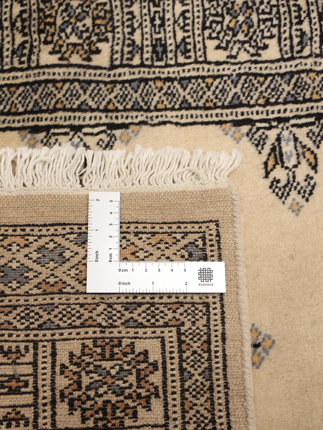 A long, cream-colored Pakistani hand-knotted runner with dark geometric motifs.