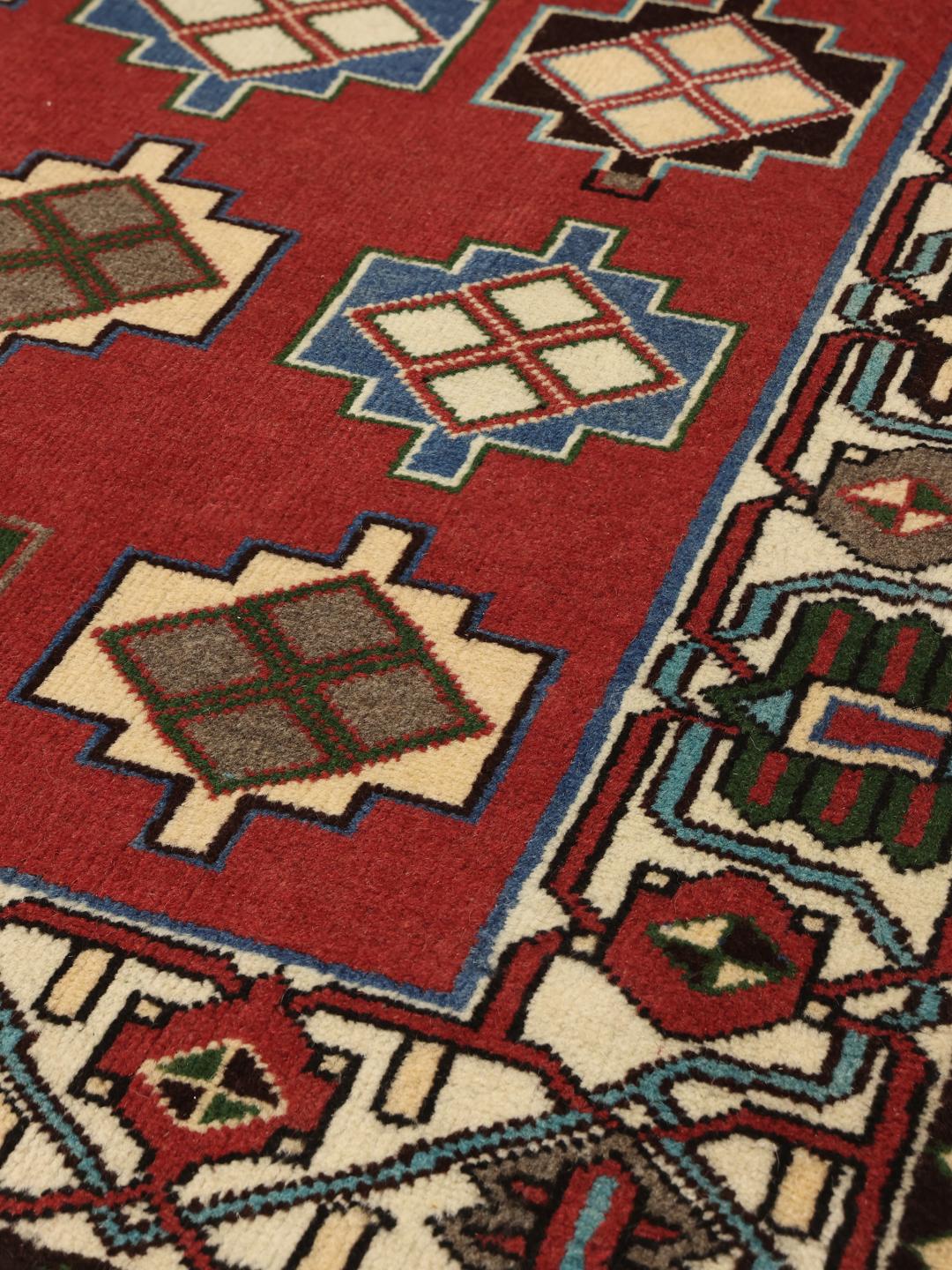 A hand-knotted Shiraz rug from the Middle East in a deep red colour with geometric patterns.