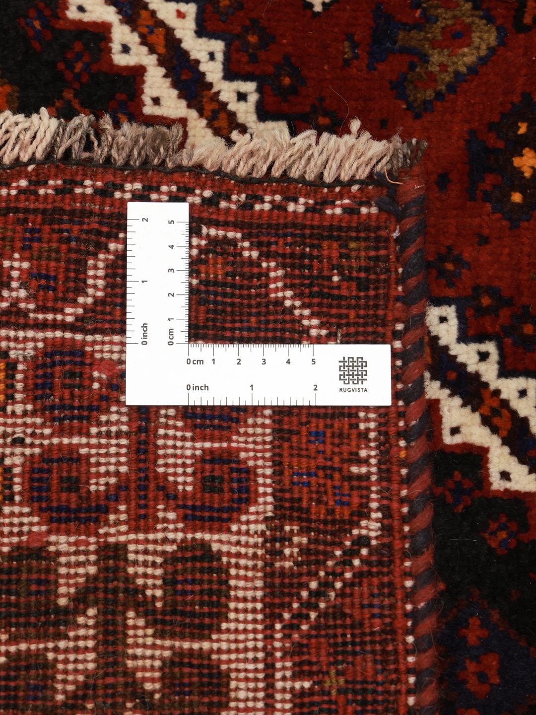 A hand-knotted Shiraz rug from the Middle East featuring a vibrant red and black geometric design.