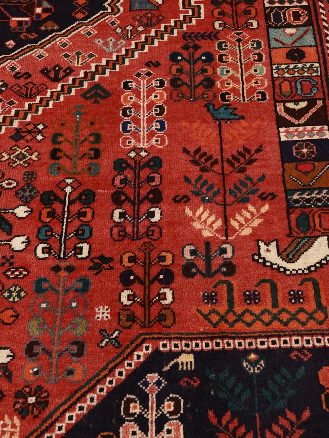 A hand-knotted Middle Eastern rug with a red field and traditional geometric patterns