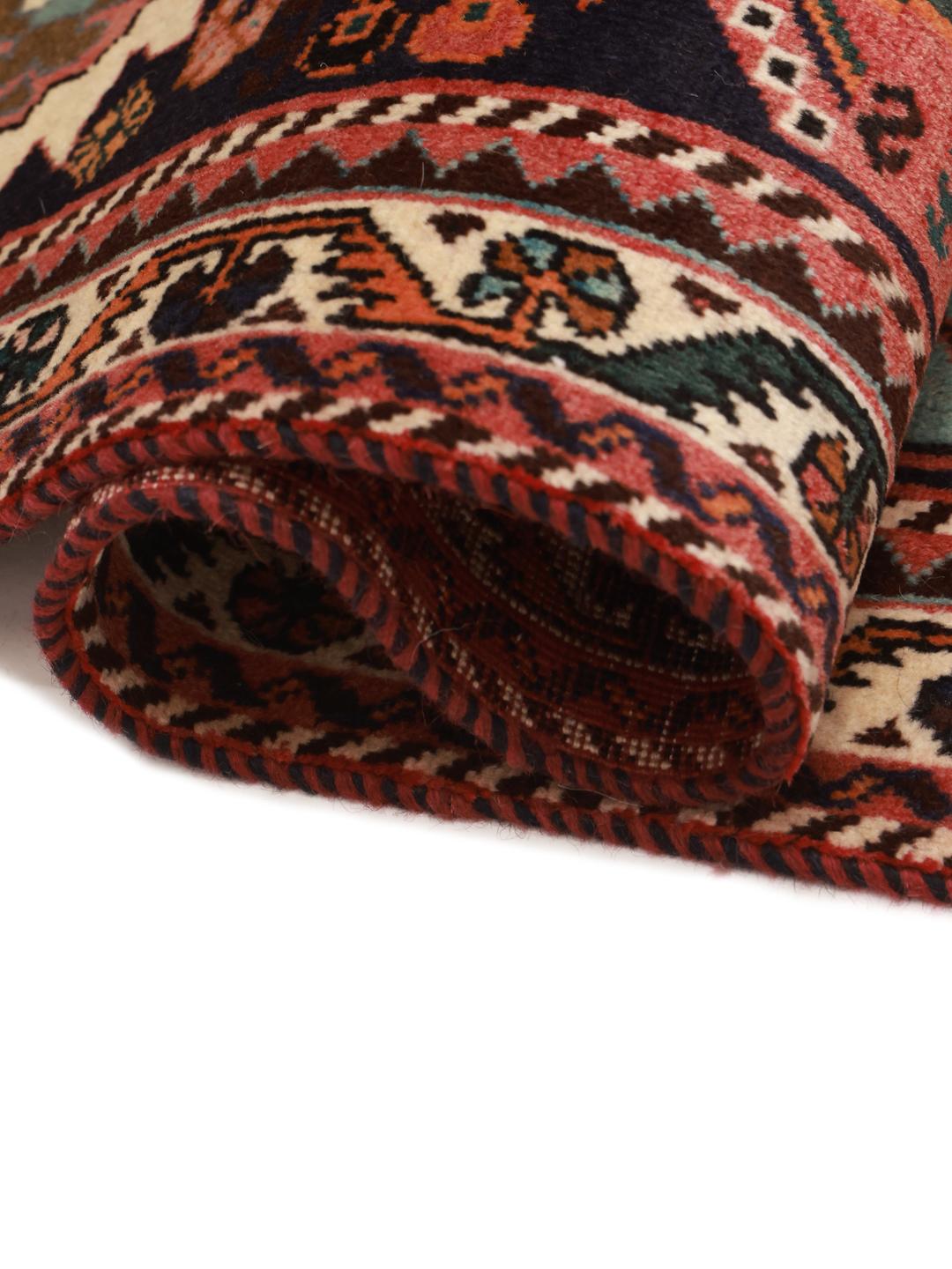 A hand-knotted Middle Eastern rug with a red field and traditional geometric patterns