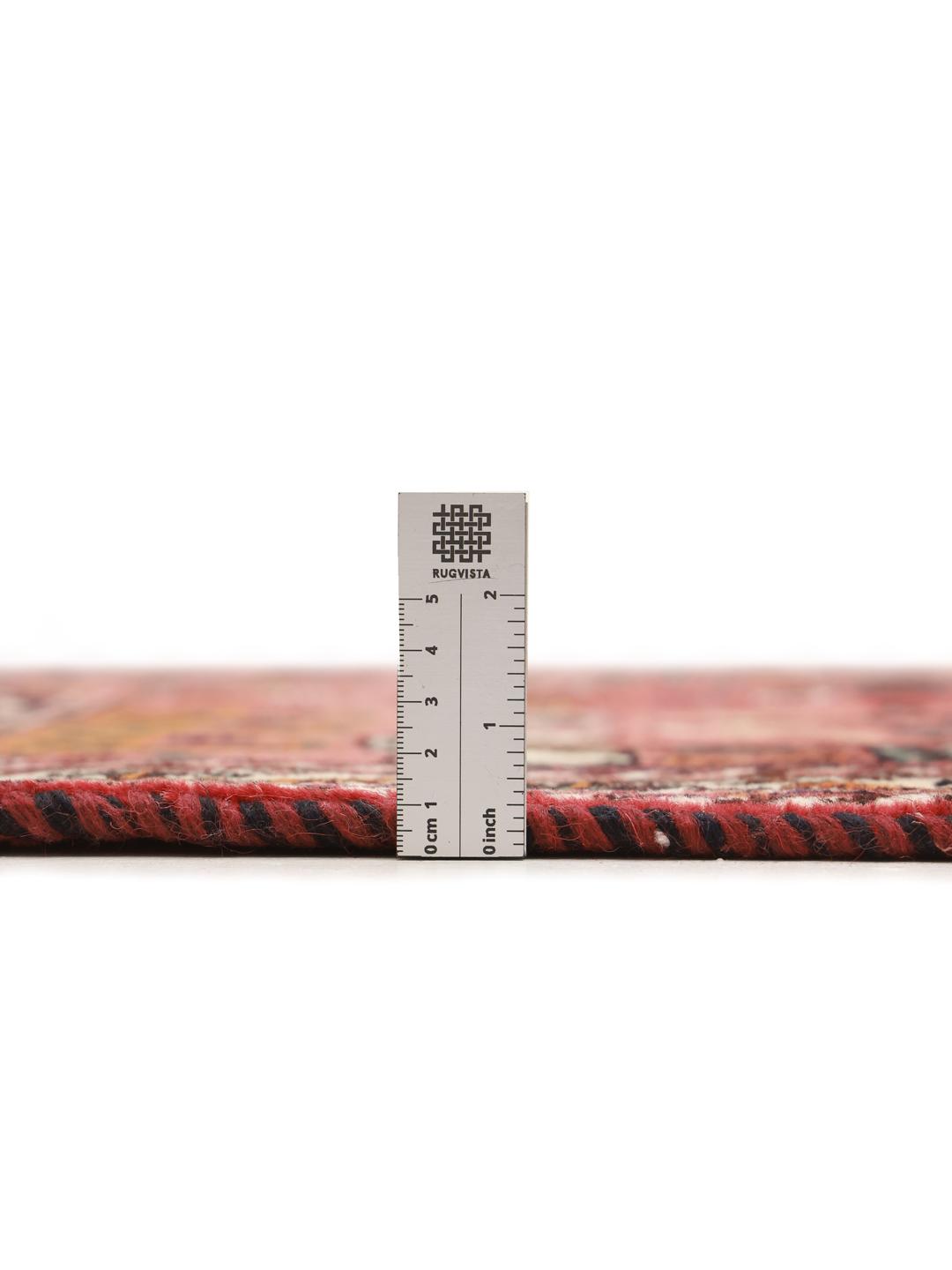 A hand-knotted Middle Eastern rug with a red field and traditional geometric patterns