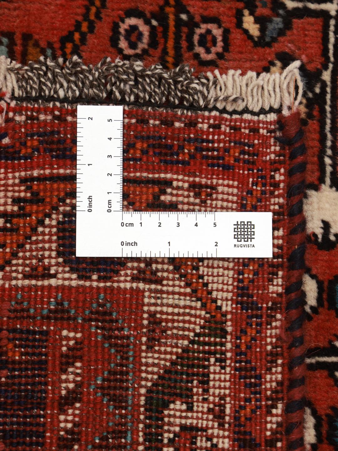 A hand-knotted Middle Eastern rug with a red field and traditional geometric patterns