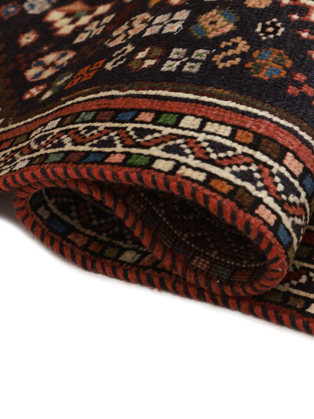 Hand-knotted Shiraz runner with a dark field and geometric motifs in red, blue, and white.