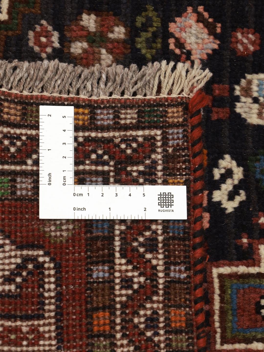 Hand-knotted Shiraz runner with a dark field and geometric motifs in red, blue, and white.
