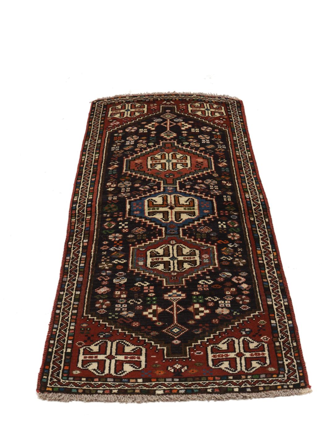 Hand-knotted Shiraz runner with a dark field and geometric motifs in red, blue, and white.