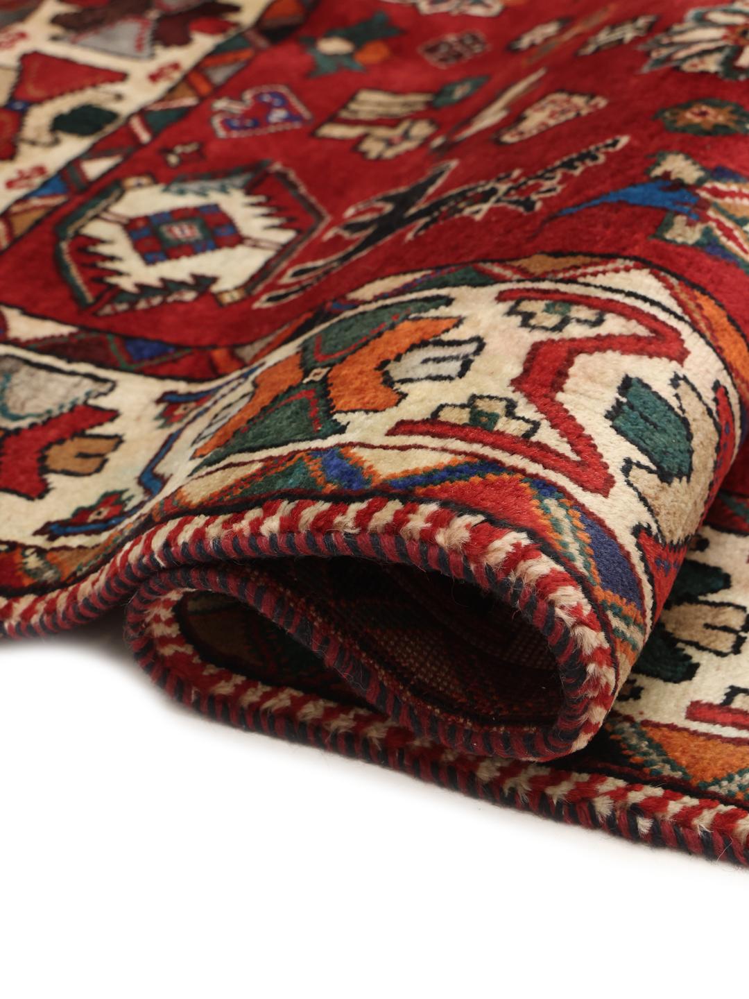 A hand-knotted Ghashghai rug from the Middle East featuring a vibrant red field with intricate geometric motifs.