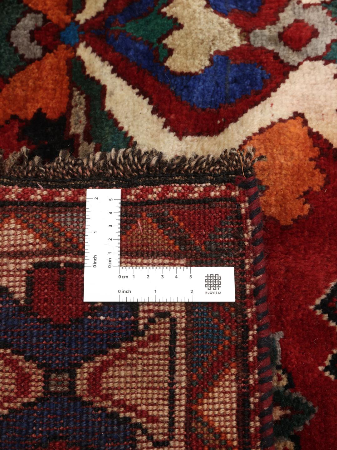 A hand-knotted Ghashghai rug from the Middle East featuring a vibrant red field with intricate geometric motifs.