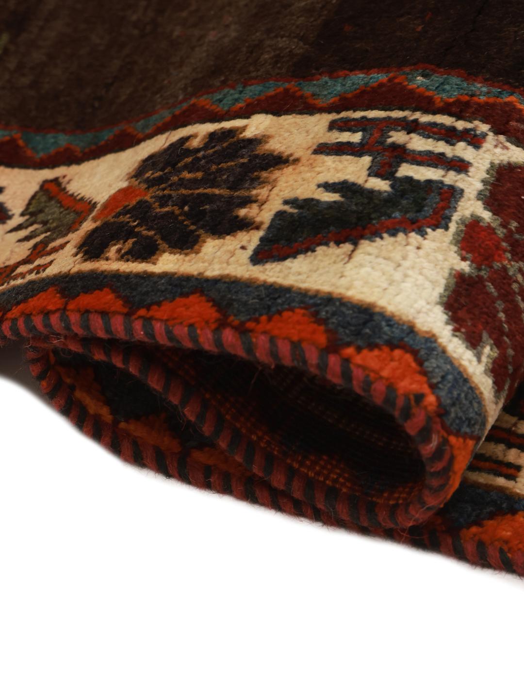 A hand-knotted Shiraz rug from the Middle East featuring a dark red field with floral motifs in a vibrant, decorative style.