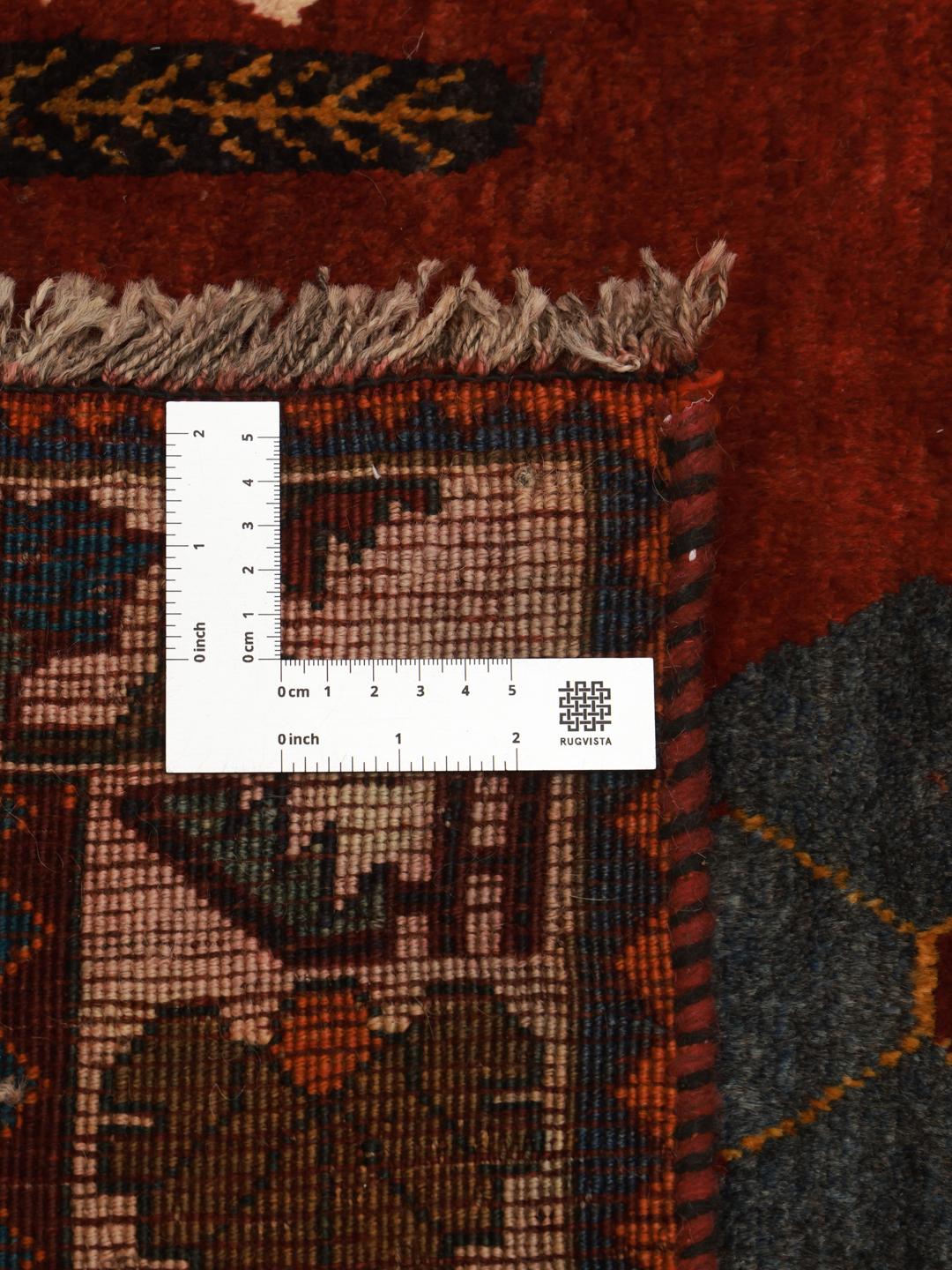 A hand-knotted Shiraz rug from the Middle East featuring a dark red field with floral motifs in a vibrant, decorative style.