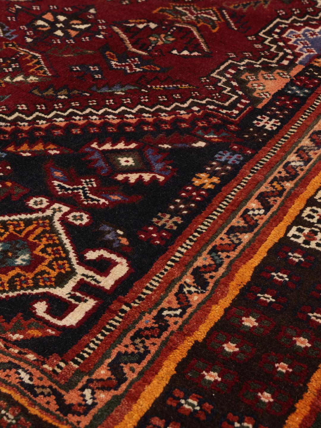 A hand-knotted Shiraz rug from the Middle East featuring a dark-red field and geometric patterns