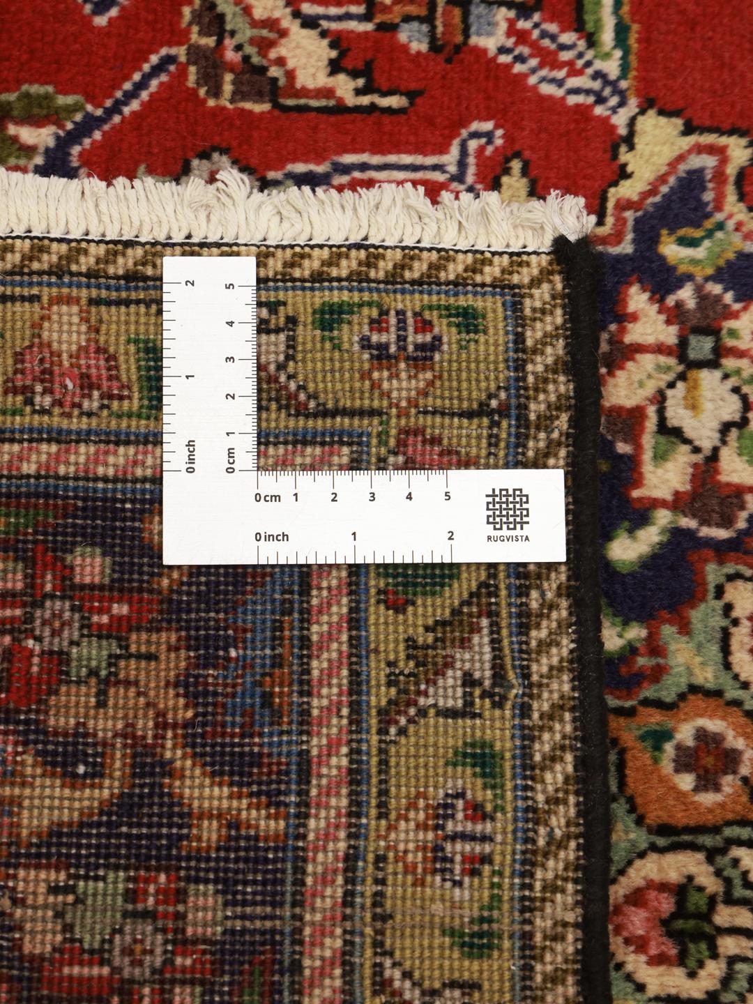 A hand-knotted Tabriz rug from the Middle East featuring a vibrant red field with a blue central medallion.