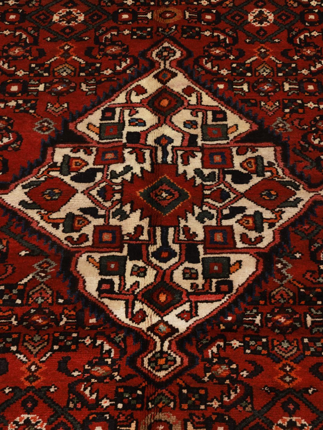 Hand-knotted Hosseinabad rug with geometric patterns in red and dark blue.