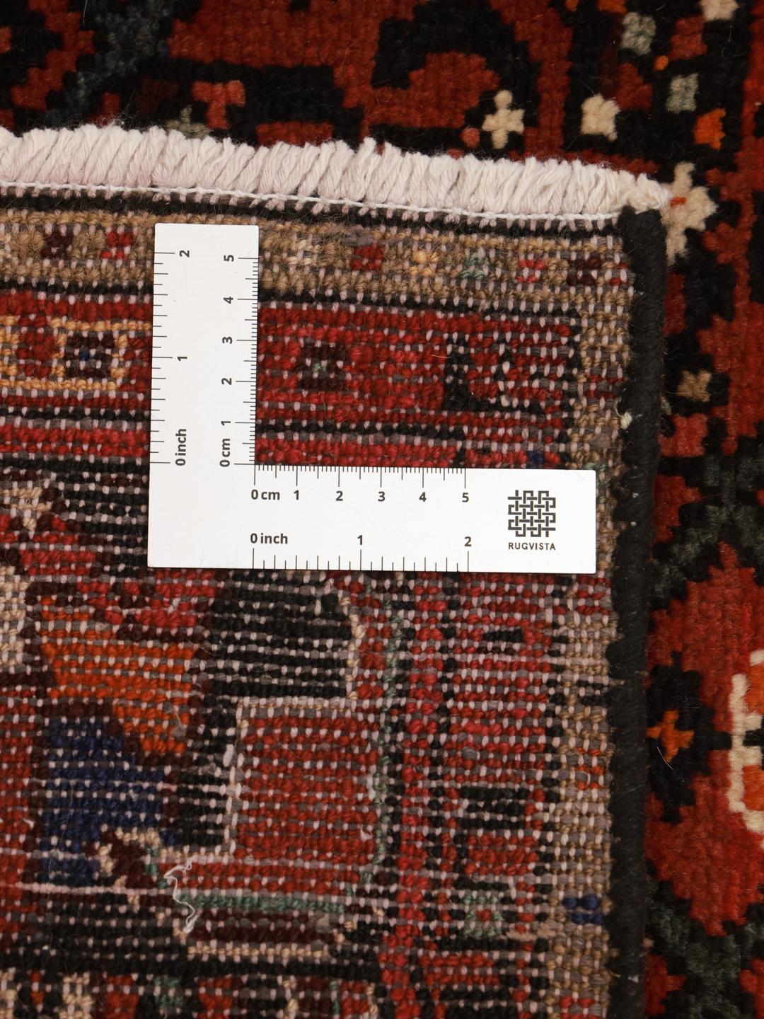 Hand-knotted Hosseinabad rug with geometric patterns in red and dark blue.