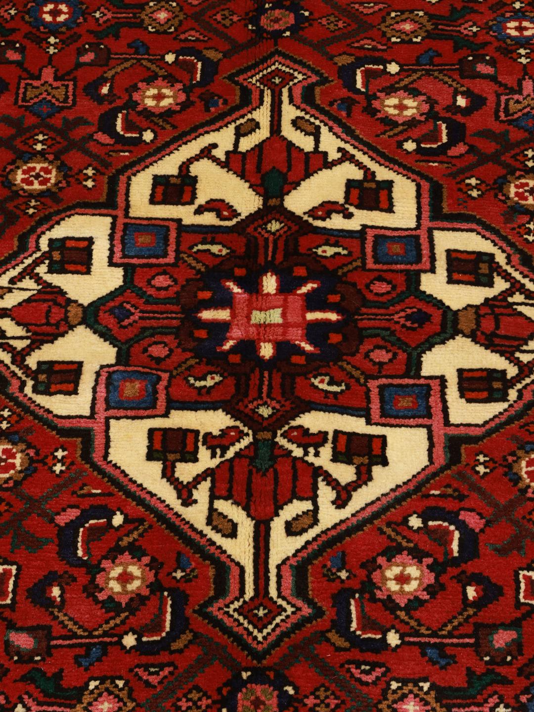 Hand-knotted Hosseinabad rug from the Middle East featuring a red field and a classic medallion pattern.