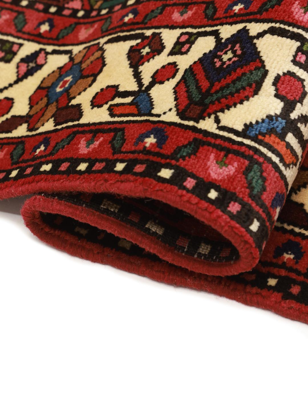 Hand-knotted Hosseinabad rug from the Middle East featuring a red field and a classic medallion pattern.