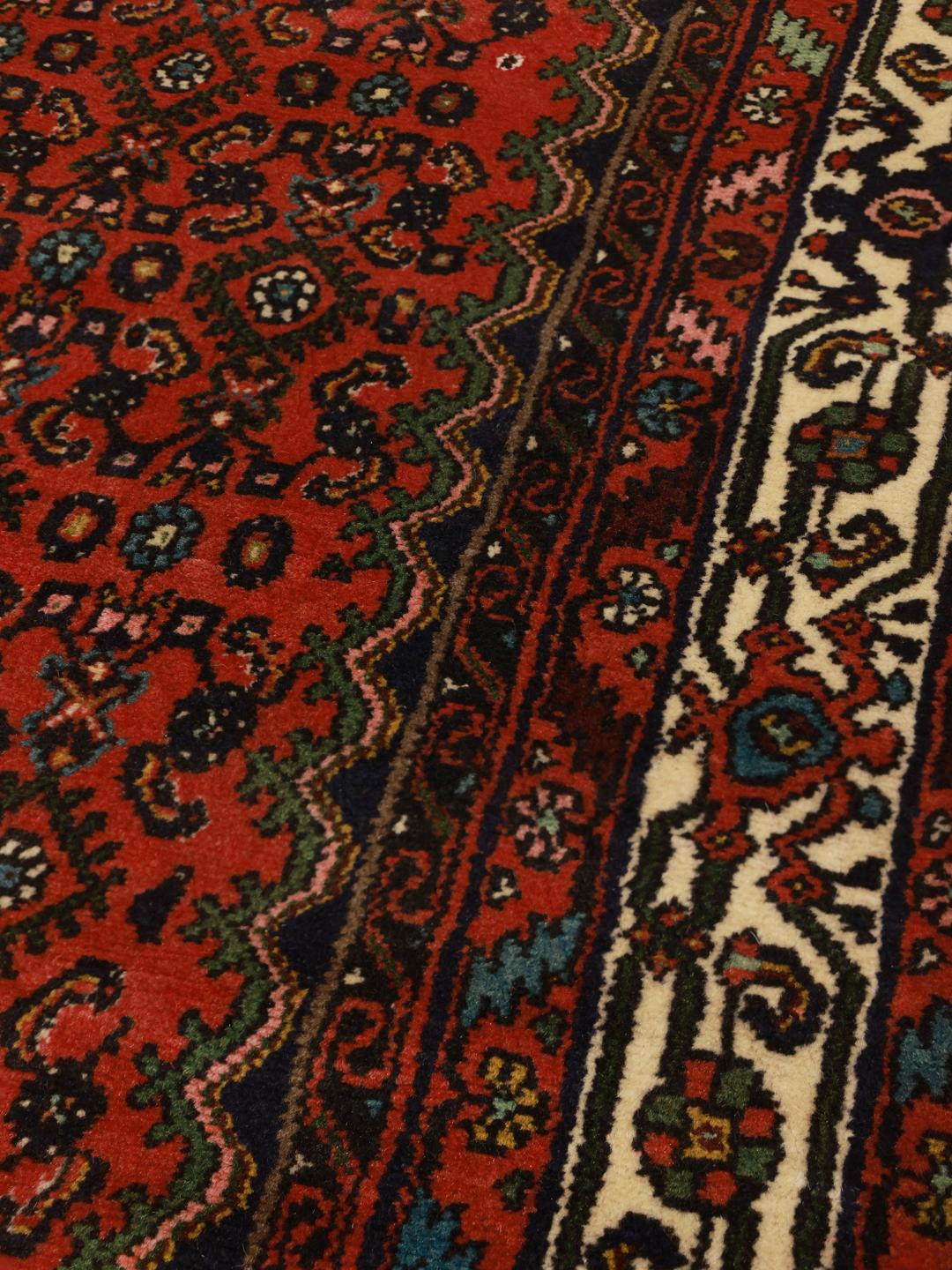 A hand-knotted red Hosseinabad rug from the Middle East.