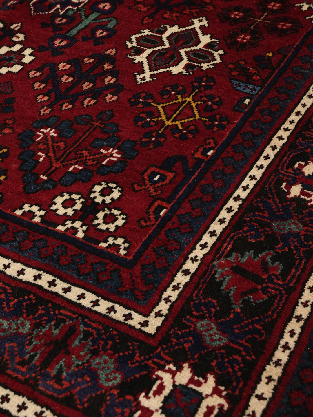 Een handgeknoopt Joshaghan-tapijt uit het Midden-Oosten in donkerrood met geometrische patronen