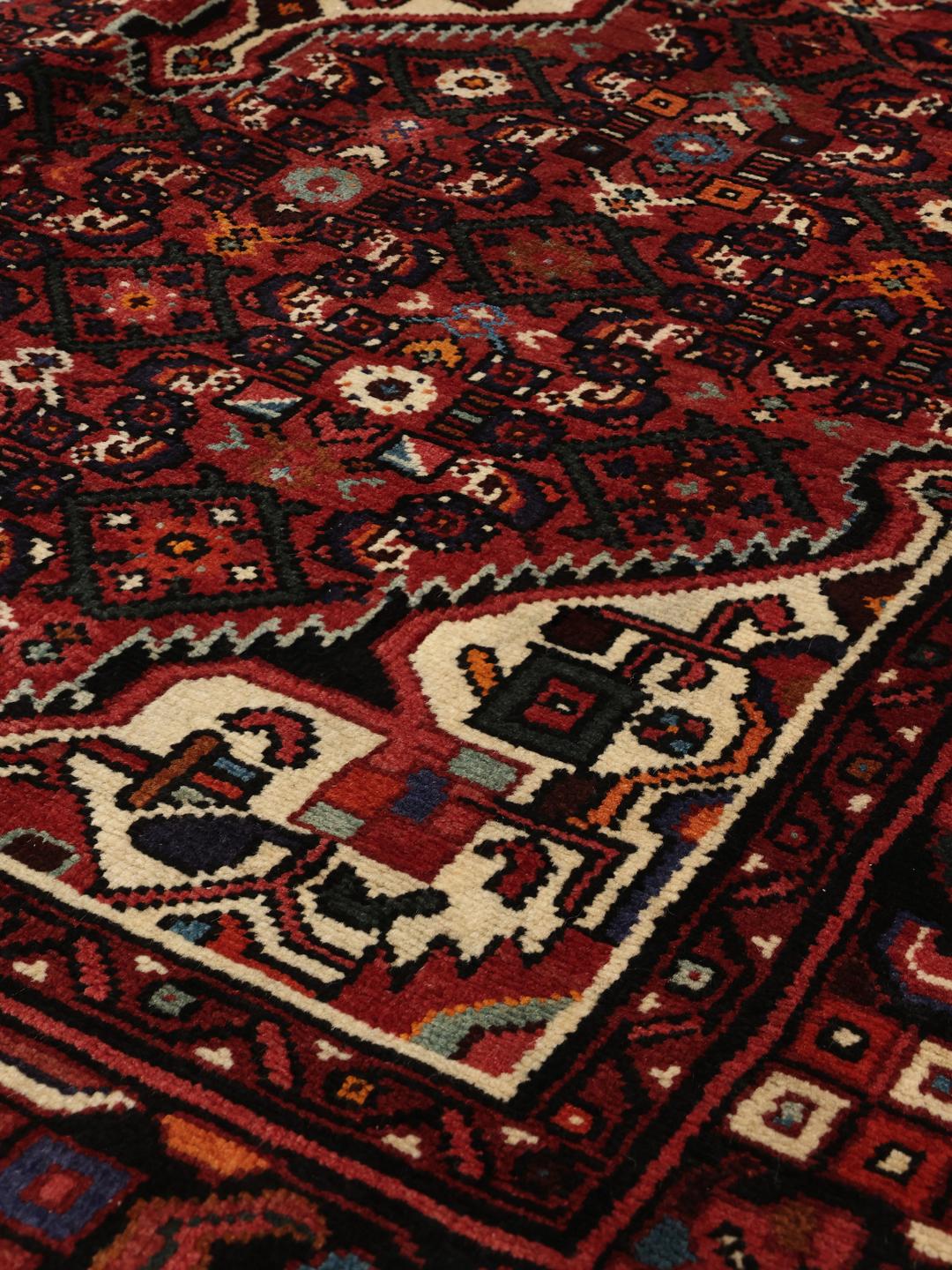Hand-knotted Hosseinabad rug with a dark-red field and traditional geometric motifs