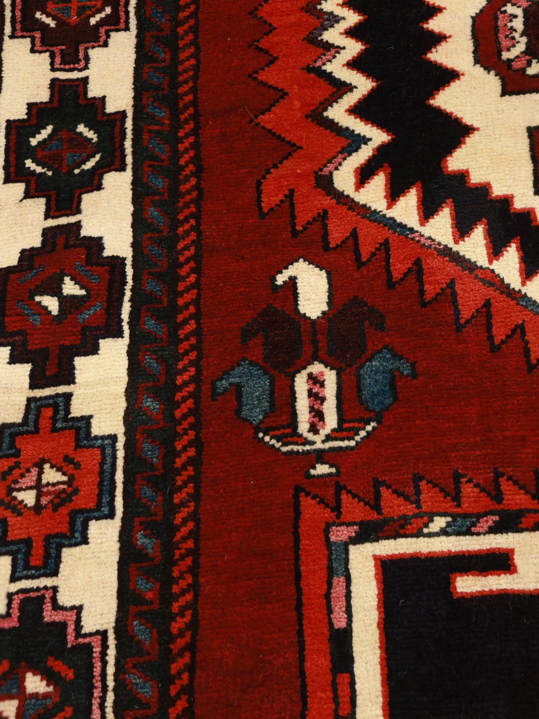 A hand-knotted Lori rug from the Middle East featuring a vibrant red and black geometric medallion design.
