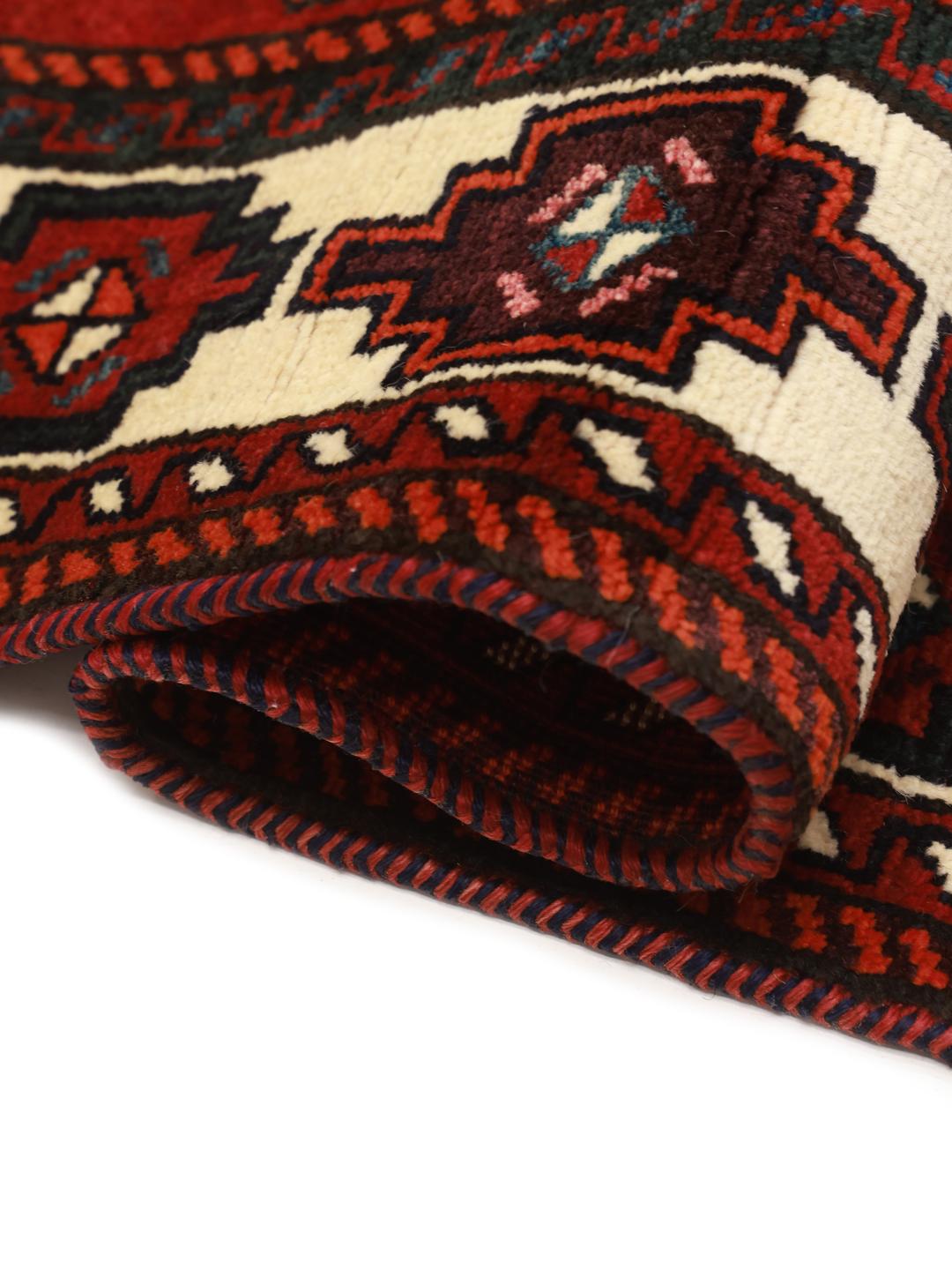 A hand-knotted Lori rug from the Middle East featuring a vibrant red and black geometric medallion design.