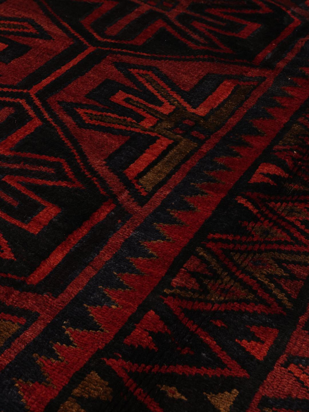 A hand-knotted Lori rug from the Middle East in dark-red and black tones with geometric patterns.