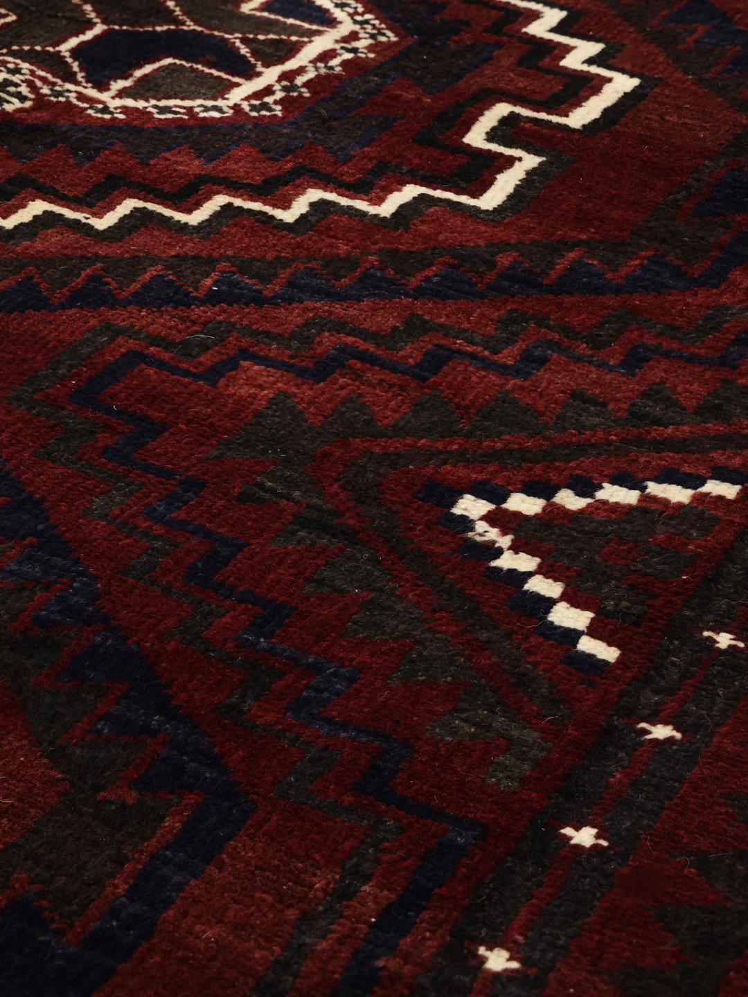 A hand-knotted Lori rug from the Middle East in dark-red with geometric patterns