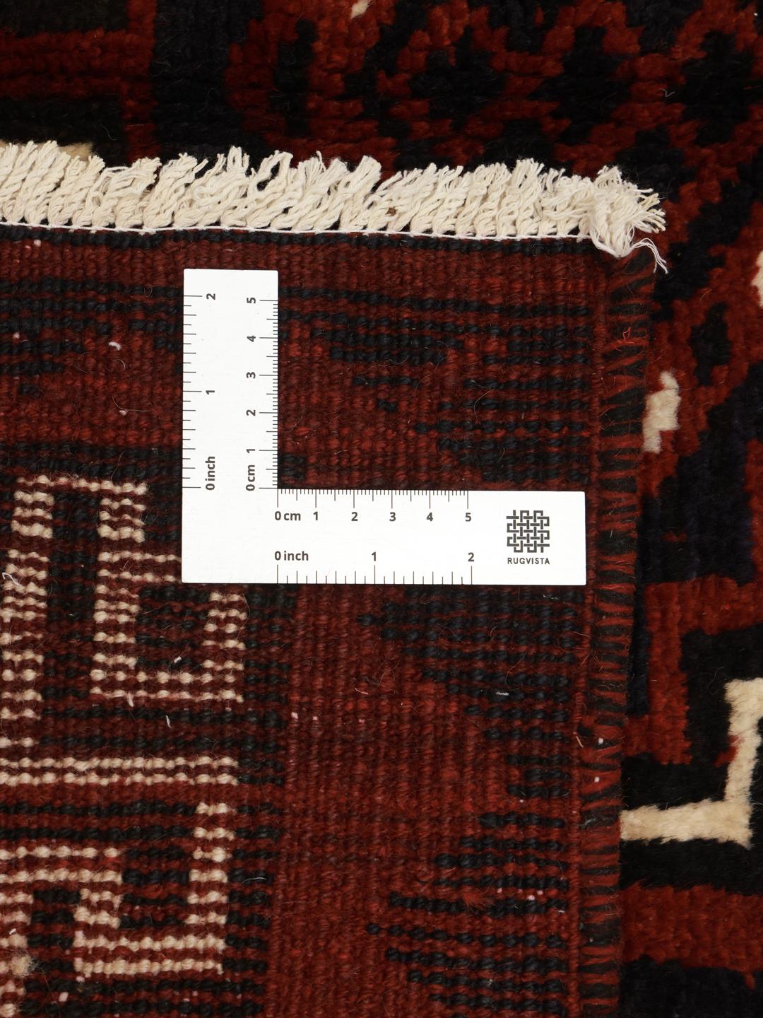 A hand-knotted Lori rug from the Middle East with a deep red and geometric pattern.