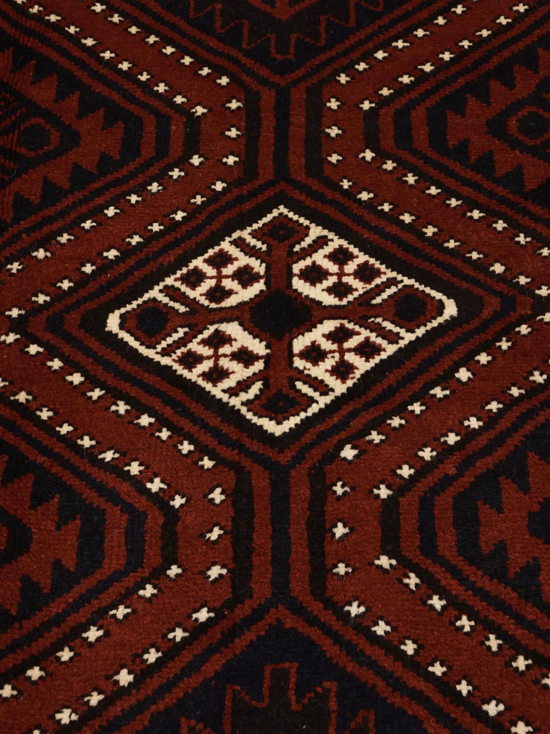 A hand-knotted Lori rug from the Middle East in dark-red with geometric patterns.