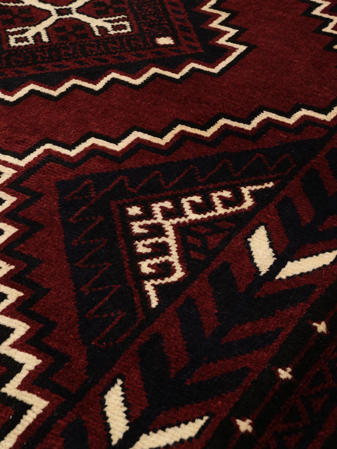 A unique hand-knotted Lori rug from the Middle East in dark-red with geometric patterns.