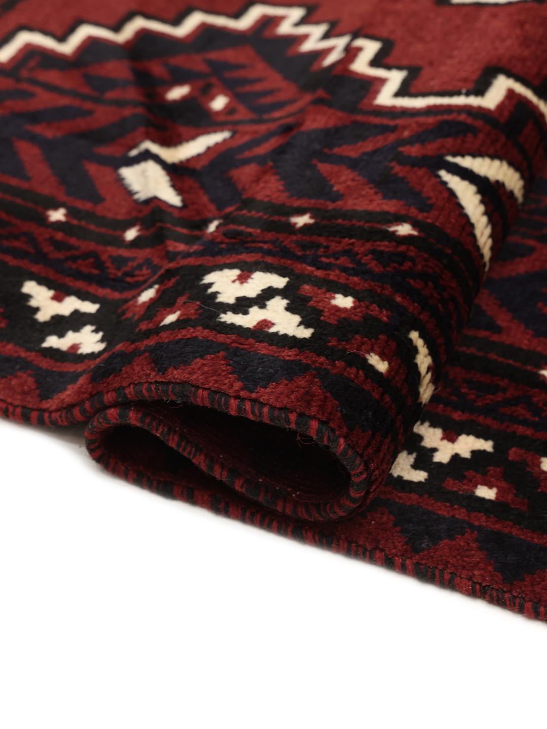 A unique hand-knotted Lori rug from the Middle East in dark-red with geometric patterns.