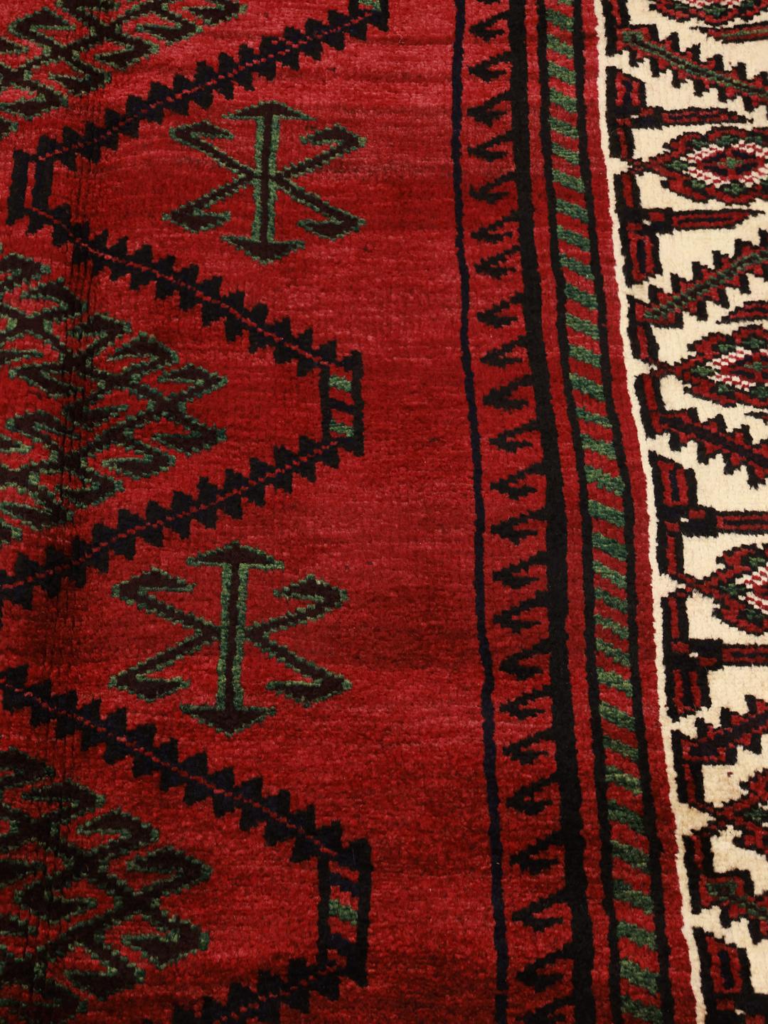A hand knotted Lori rug from the Middle East with a deep red field and geometric patterns.