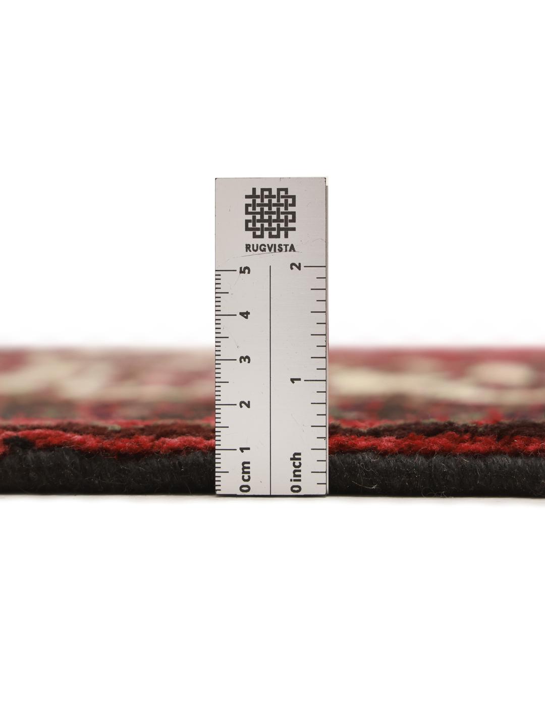A hand knotted Lori rug from the Middle East with a deep red field and geometric patterns.
