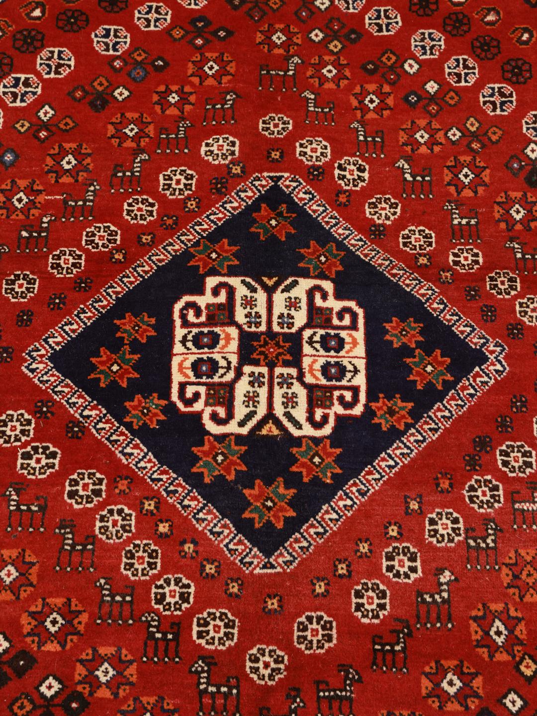 A hand-knotted Ghashghai rug from the Middle East featuring a red and dark-blue colour palette.