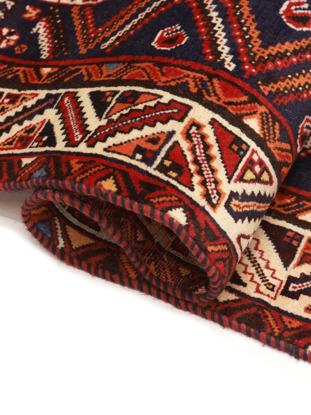A hand-knotted Ghashghai rug from the Middle East featuring a red and dark-blue colour palette.