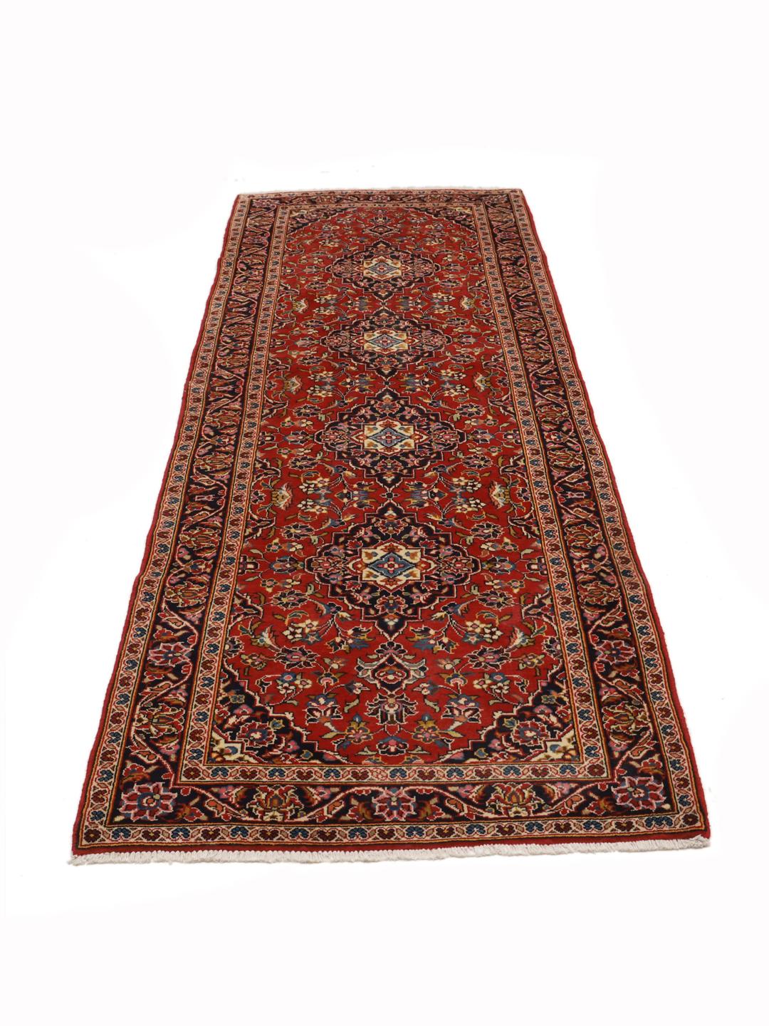 A hand-knotted Middle Eastern Keshan runner in red with floral medallion patterns.