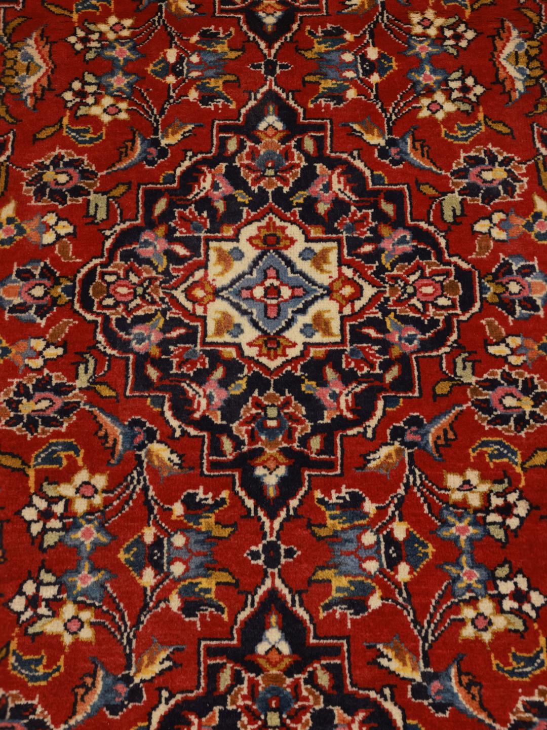 A hand-knotted Middle Eastern Keshan runner in red with floral medallion patterns.