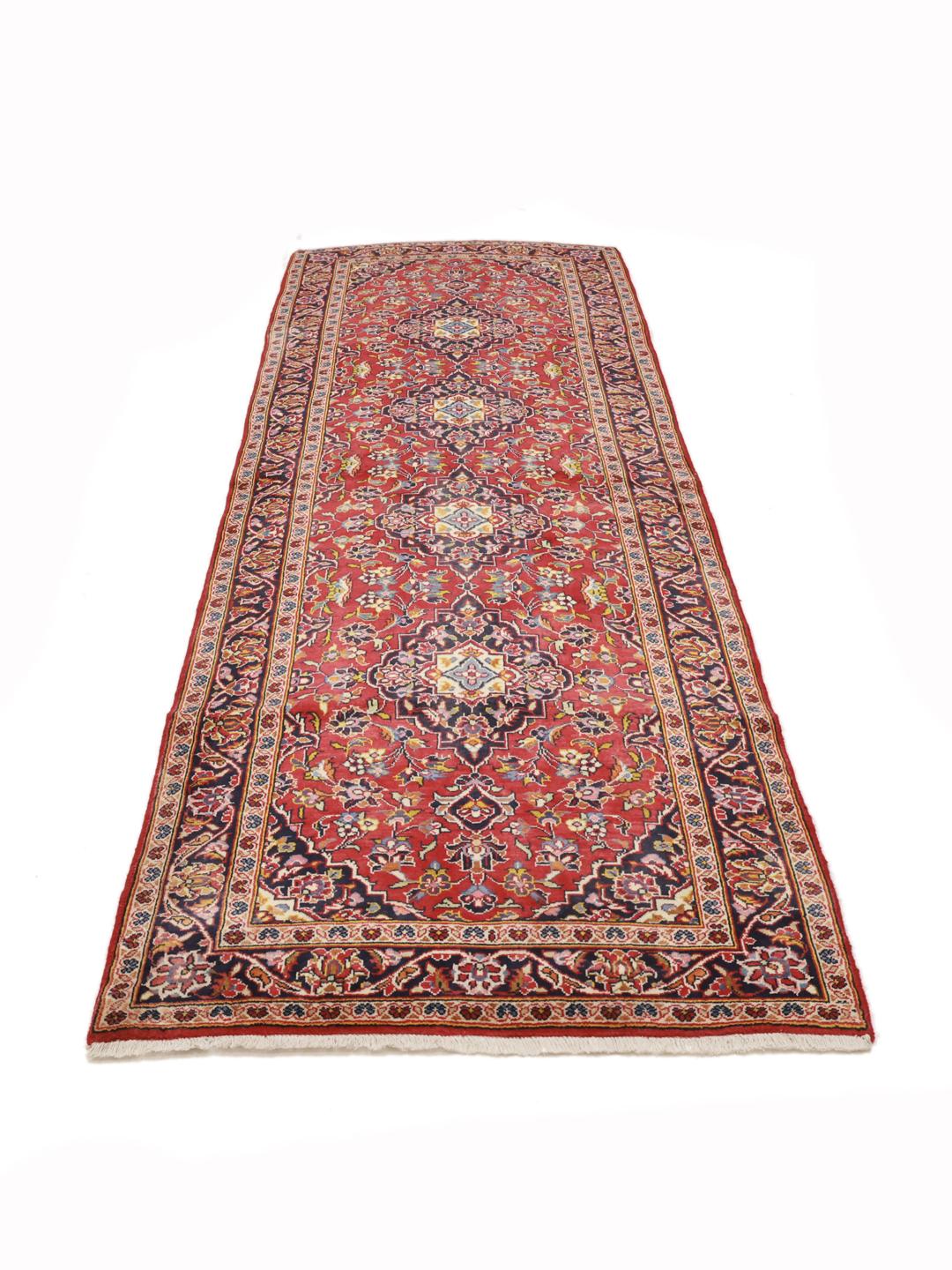 A hand-knotted Middle Eastern Keshan runner in red with floral medallion patterns.
