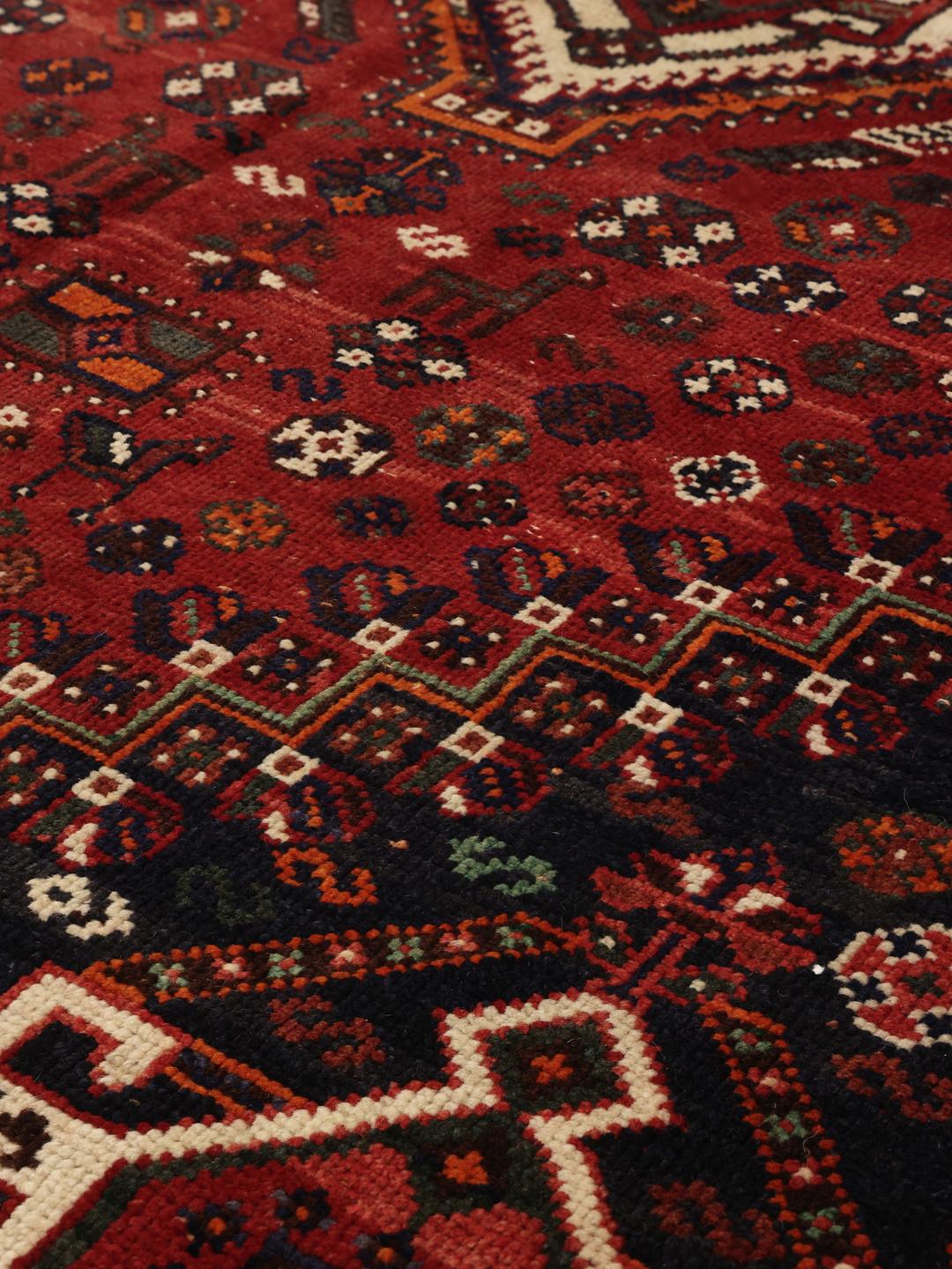 A hand-knotted Ghashghai rug from the Middle East featuring a vibrant red and black colour scheme.
