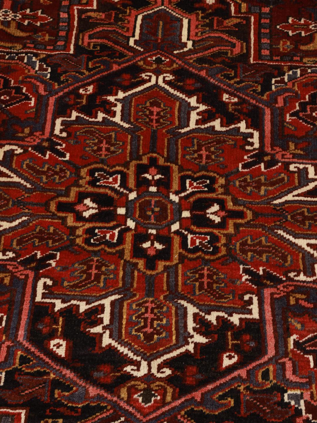 A hand-knotted Heriz rug from the Middle East in deep red and dark blue tones.