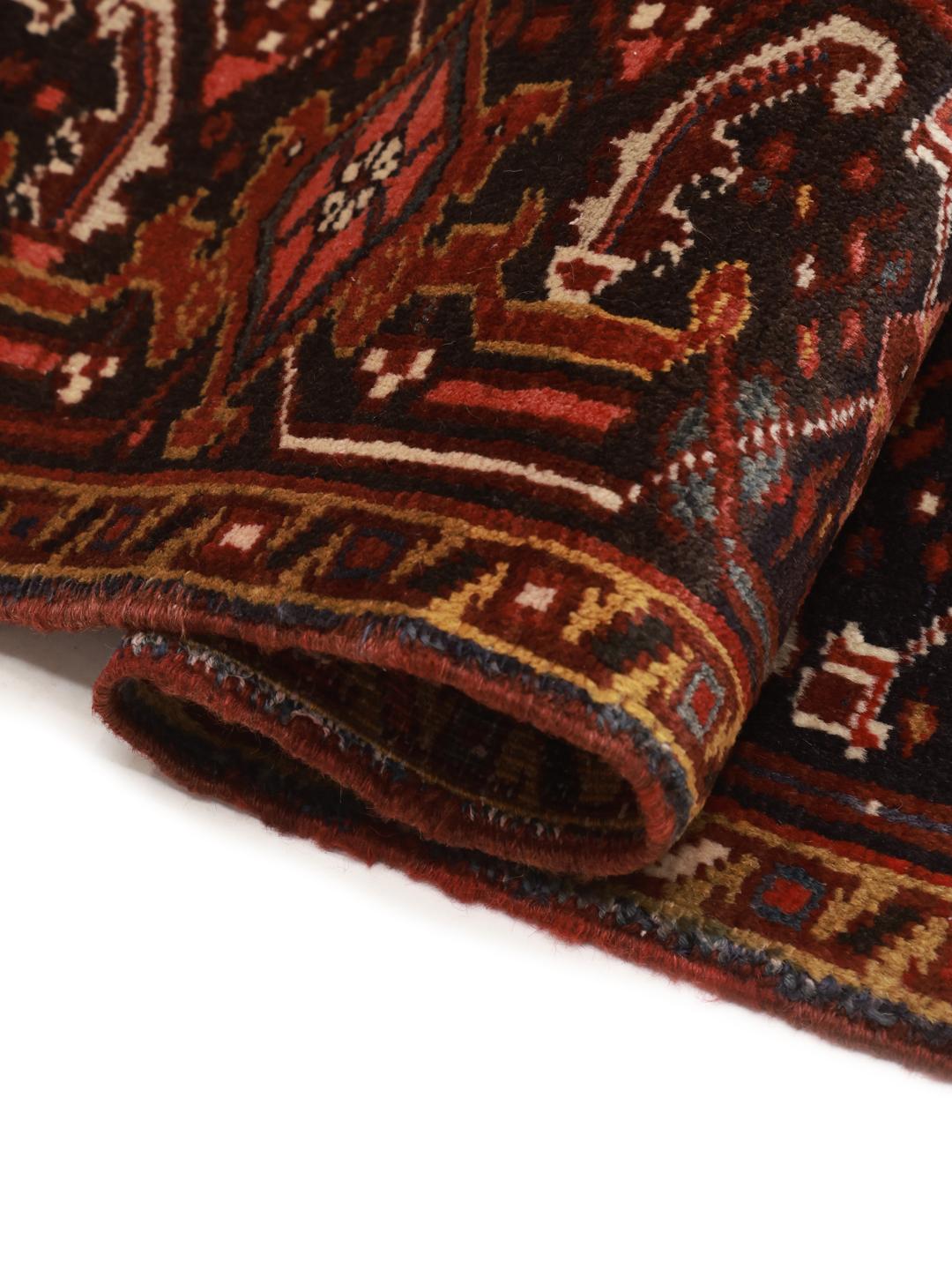 A hand-knotted Heriz rug from the Middle East in deep red and dark blue tones.