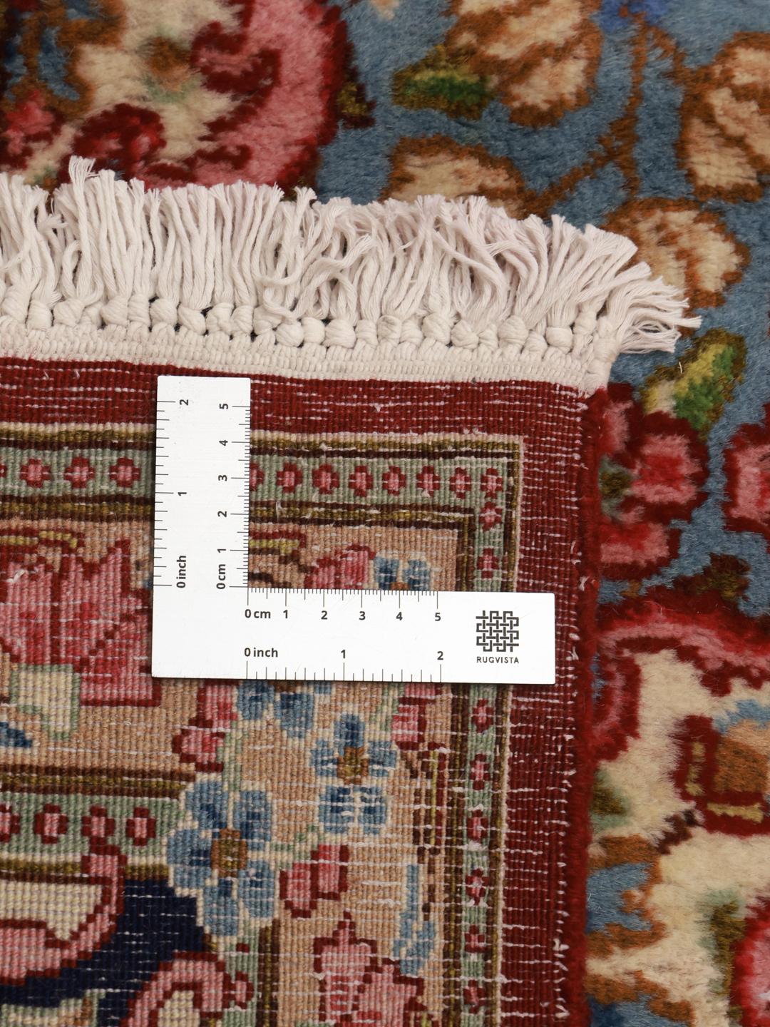 A large rectangular Kerman rug from the Middle East with a deep red field and intricate floral motifs.