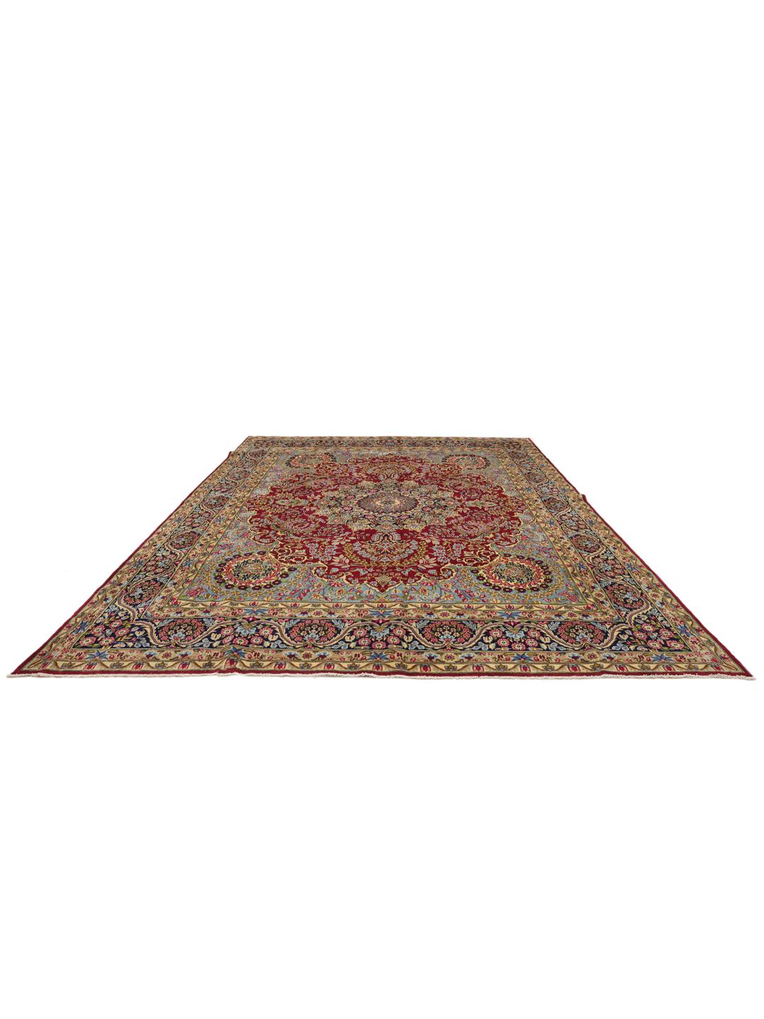 Een groot rechthoekig Kerman-tapijt uit het Midden-Oosten met een levendig rood en blauw bloemenpatroon.