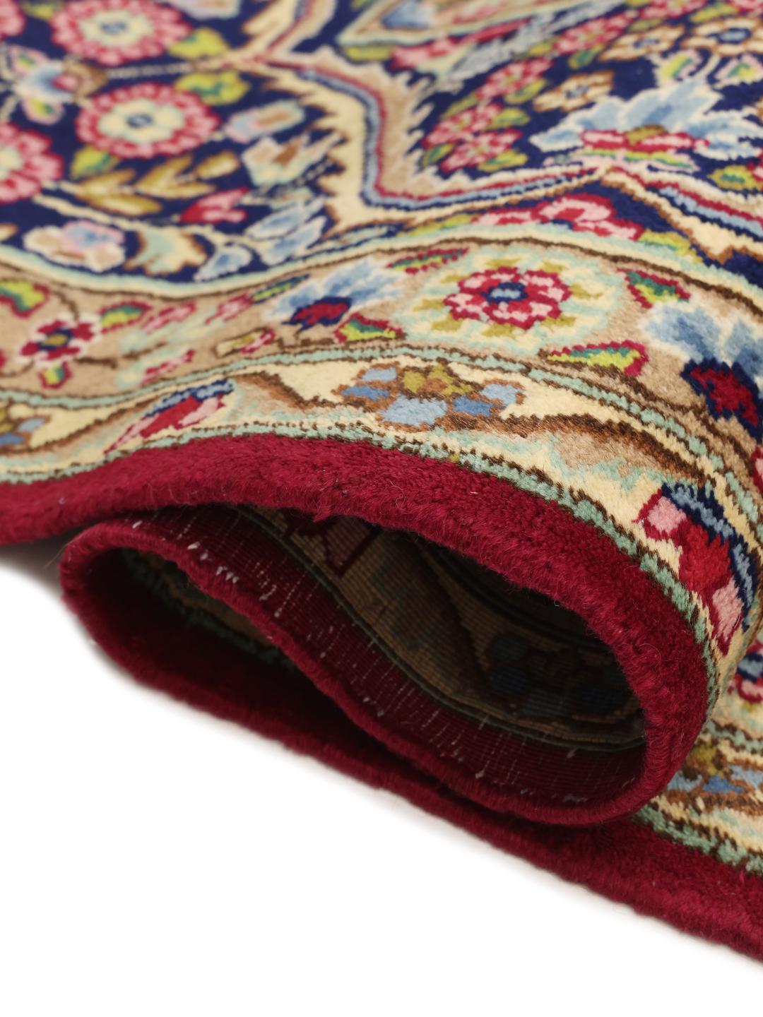 Een groot rechthoekig Kerman-tapijt uit het Midden-Oosten met een levendig rood en blauw bloemenpatroon.