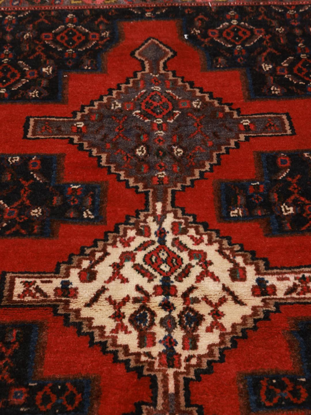 A hand-knotted Senneh rug from the Middle East with a bold red and black geometric design.