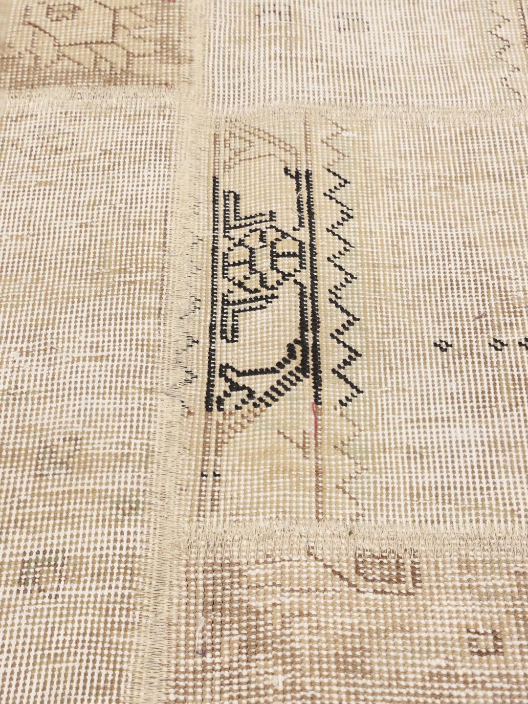 Et neutralfarvet patchworktæppe fra Mellemøsten med lav luv af uld og komplekse geometriske motiver.