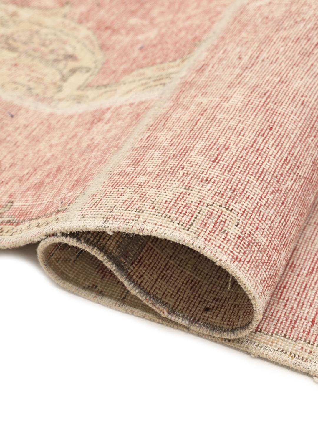Et kvadratisk patchwork-tæppe med lyserøde og beige blomstermotiver og en patineret finish.