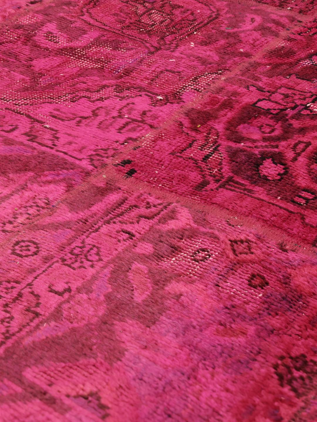 Een levendig vierkant patchwork tapijt met dieproze en rode tinten, handgeknoopt in het Midden-Oosten.