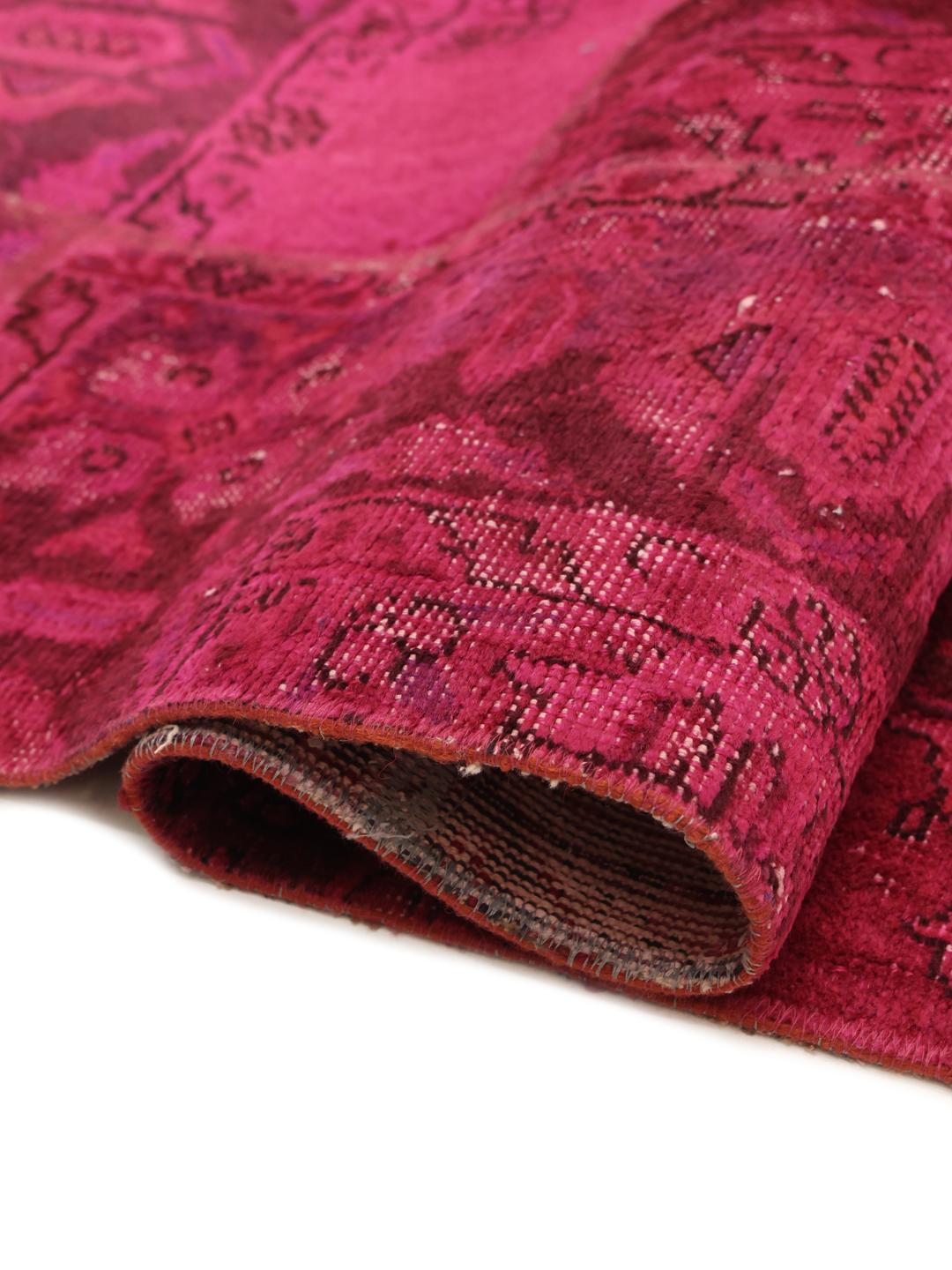 Een levendig vierkant patchwork tapijt met dieproze en rode tinten, handgeknoopt in het Midden-Oosten.