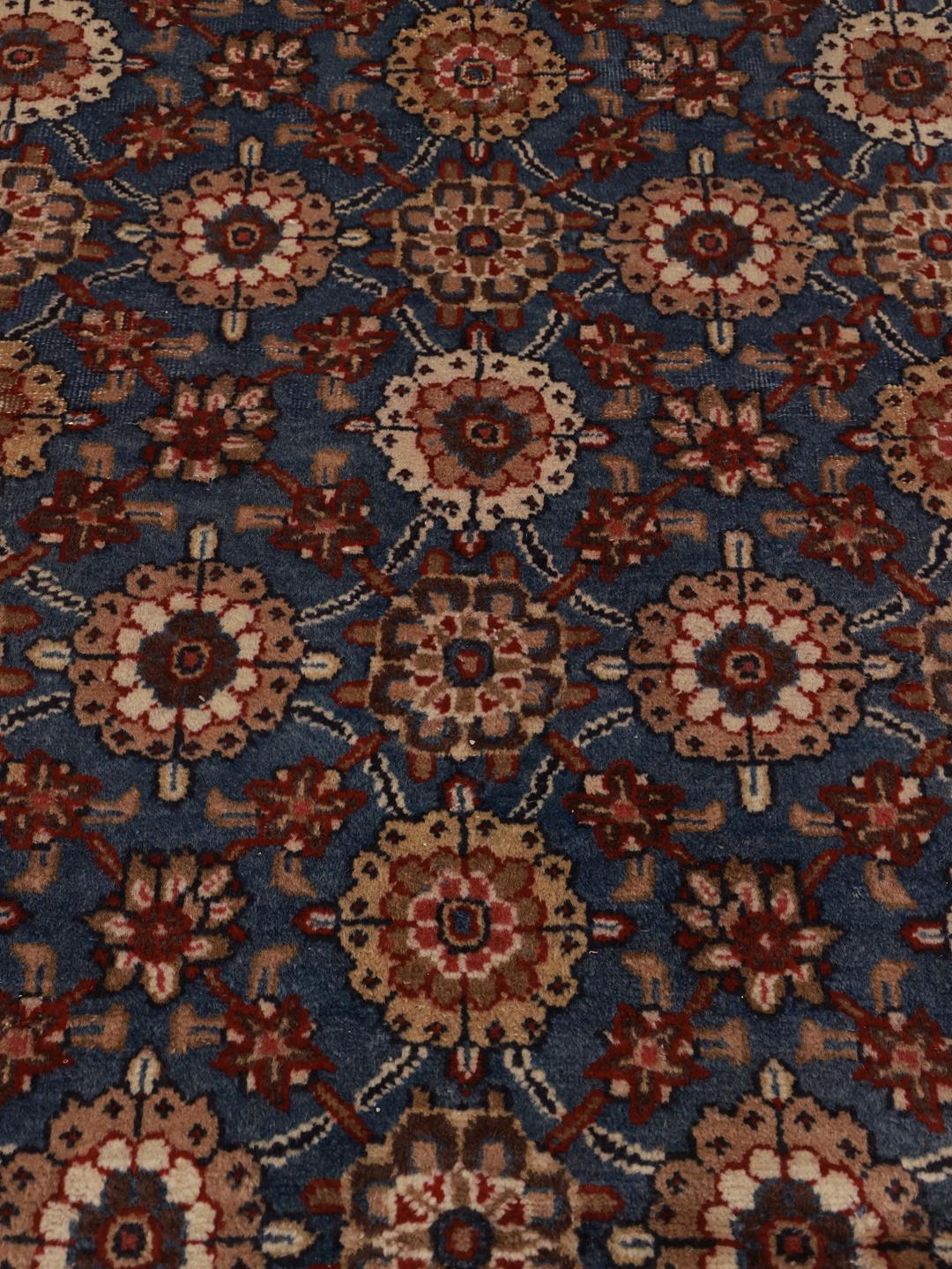 Hand-knotted Sarouk rug from the Middle East featuring a blue field with floral motifs.